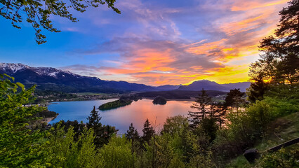 Obraz na płótnie Canvas Panoramic sunset view on Lake Faak from Taborhoehe in Carinthia, Austria, Europe. Surrounded by high Austrian Alps mountains. Water surface reflecting soft sunlight. Remote alpine landscape in summer