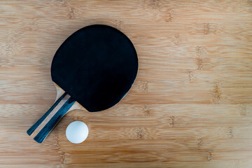 Paletka i piłeczka do tenisa stołowego leżąca na blacie bambusowym - obrazy, fototapety, plakaty