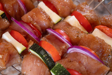 Raw meat with vegetables on skewers close-up