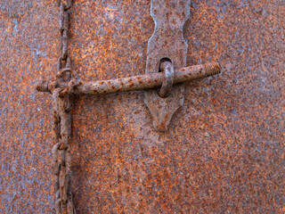 A rusty metal latch and a bolt on a chain