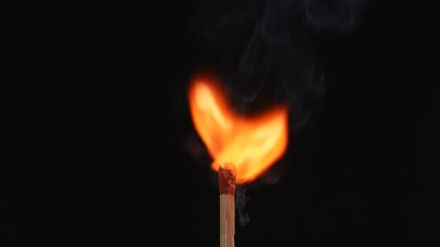 Macro video captures the moment of ignition of the match and its flame. From the flare up to the bright burning. The red sulfur of the match flashes fire and the wood burns. Symbolizing energy.