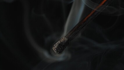 Macro shot of a black charred match and clouds of white smoke. Burned extinguished wooden match on...