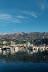 Fototapeta na wymiar Yachts moored off the coast with high-rise buildings at the foot of the mountains