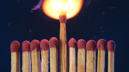 A row of matches with red gray. The center match flares up and catches fire. A tongue of flame...