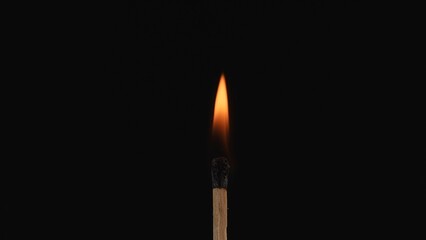 Macro shot of a burning match against a dark studio background. The flame of the burning match...