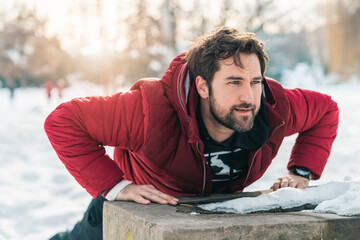 Focused sportsman doing push-up challenge outdoors on cold winter day.