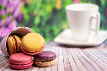 Sweet colorful macarons. Traditional french macaroons. Tasty desser,macaroons ,macarons poured from a small bucket on a wooden background, colorful spring