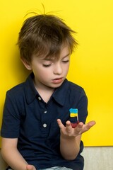 a boy of European appearance is holding a plasticine boat with the flag of Ukraine in his hands