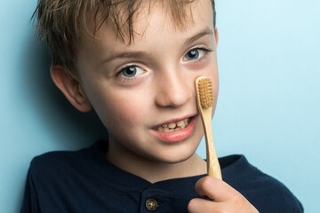 a boy of European appearance holds a bamboo toothbrush in his hands