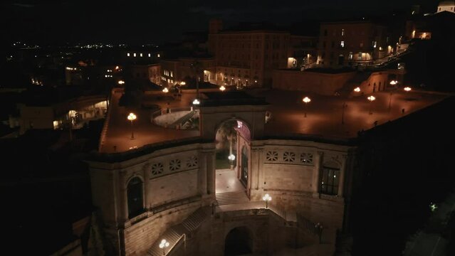Aerial shot at night of Italian historic city Cagliari (Casteddu, Caralis), Bastione of Saint Remy, Terrazza Umberto I, Mediterranean Sea, Sardinia, Italy, Europe. 4K drone shot.