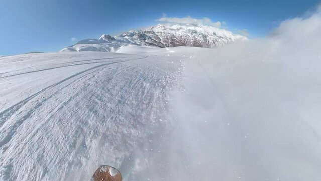 POV: Snowboarder on a scenic powder ride in the picturesque snowy Albanian Alps on a sunny day. Incredible mountain terrains for joyful snowboard rides in the embrace of magnificent alpine landscape.
