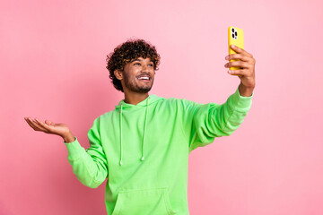 Photo of young hipster arabian guy wearing green hoodie showing new alternative youtube app make...