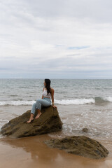 Latin girl sitting on a stones in front of the sea