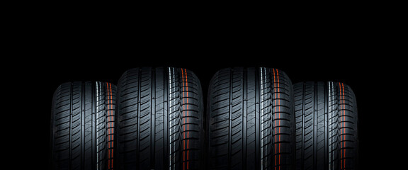 Four new car tires treads on black background. Copy space for workshops advertising brochures.	