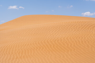 Fototapeta na wymiar Sand dunes with blue sky and a cloud in Morocco