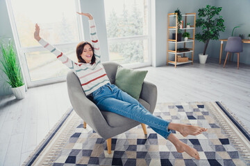 Full size photo of peaceful cheerful girl closed eyes sit stretching armchair calm atmosphere...