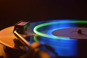 Vinyl disc on the player plays music in the dark photo with light effects at long exposure 
