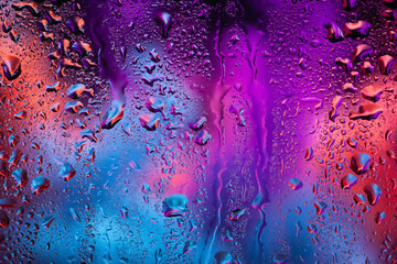 Raindrops on the window. Water drops on glass. Abstract background. Multicolored smoke. Texture of...