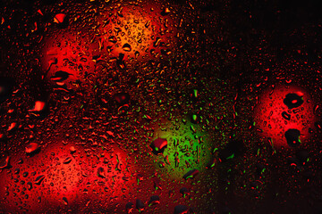 Raindrops on the window. Water drops on glass. Abstract background. Street lights. Texture of drops. Selective focus.