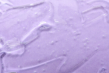 Clear cosmetic gel on violet background, top view