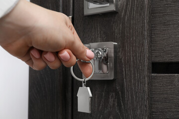 Woman unlocking door with key, closeup view