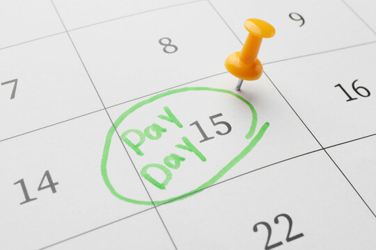 Calendar page with orange pin on payday date, closeup