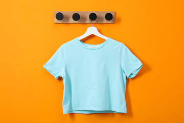 Hanger with light blue T-shirt on orange wall