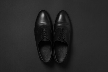 Pair of leather men shoes on black background, top view