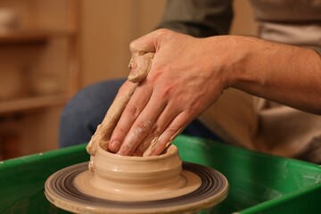 Clay crafting. Man making bowl on potter's wheel indoors, closeup