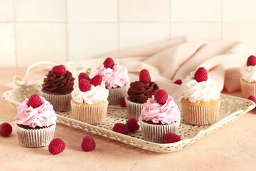 Tray of tasty cupcakes with raspberries on table