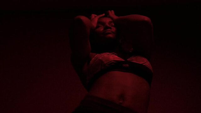 Slow motion of black woman dancer performs dancehall under red lights	