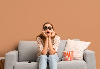 Emotional young woman in 3d glasses watching movie while sitting on sofa in living room