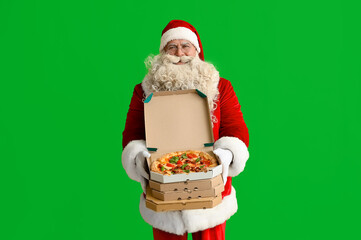 Santa Claus with boxes of tasty pizza on green background