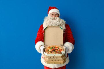 Santa Claus with boxes of tasty pizza on blue background