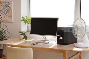 Comfortable workspace with modern computer and portable power station