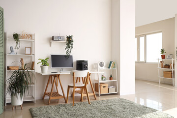 Comfortable workspace with modern computer and portable power station in contemporary room