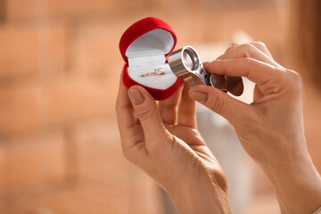 Female jeweler examining engagement ring in workshop, closeup
