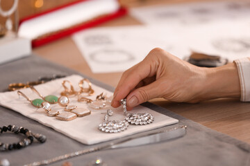 Female jeweler with earrings in workshop, closeup