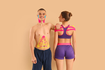 Young couple with physio tape on beige background