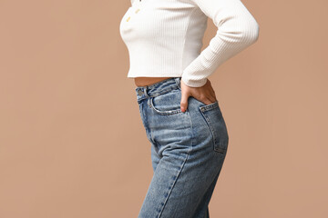 Beautiful young Asian woman in stylish jeans on brown background, closeup - obrazy, fototapety, plakaty