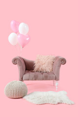 Cozy armchair with pouf and heart-shaped balloons on pink background. Valentine's Day celebration