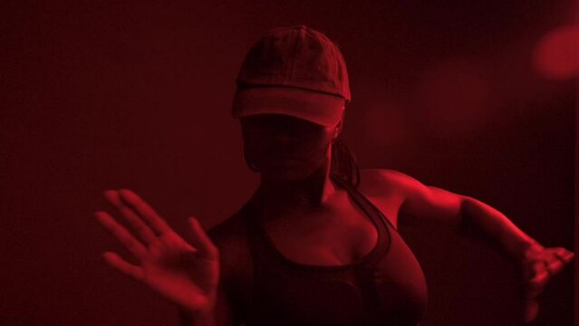 Slow motion of black woman dancer performs dancehall under red lights	