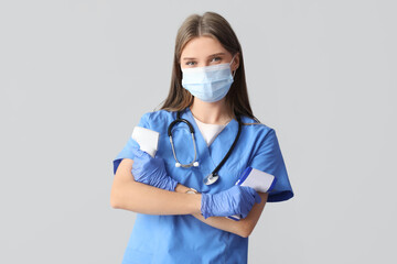 Beautiful doctor in medical mask with infrared thermometers on light background