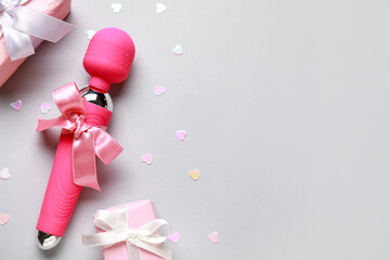 Vibrator with bow and gift boxes on grey background. Valentine's Day celebration