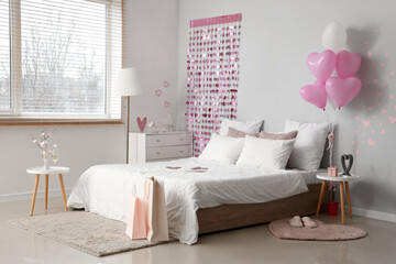 Fototapeta na wymiar Interior of light bedroom with cozy bed and heart-shaped balloons. Valentine's Day celebration
