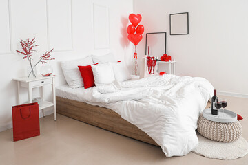 Interior of light bedroom with glasses of wine, heart-shaped balloons and red lingerie in shopping bag. Valentine's Day celebration