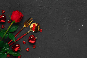 Cutlery with hearts and red rose on black background. Valentine's Day celebration