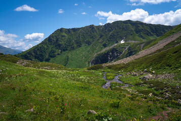 The valley of the Malaya Dukka River surrounded by the mountains of the North Caucasus and the tourist trail to the Dukka Lakes on a sunny summer day, Arkhyz, Karachay-Cherkessia, Russia