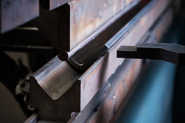 Bending press operates with metal sheet in plant workshop