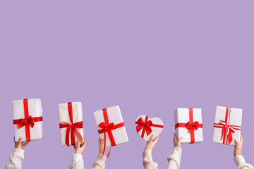 Female hands with gift boxes on lilac background. Valentine's Day celebration